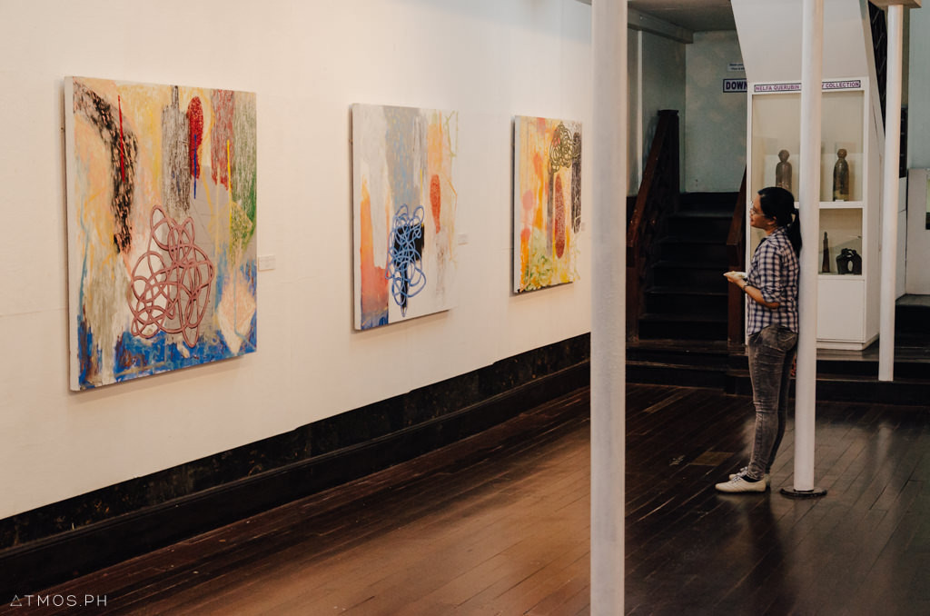 A student thoroughly examines the recent works at the exhibit.